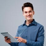 Homem segurando tablet e sorrindo por saber os benefícios de fazer vendas consultivas