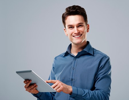 Homem segurando tablet e sorrindo por saber os benefícios de fazer vendas consultivas