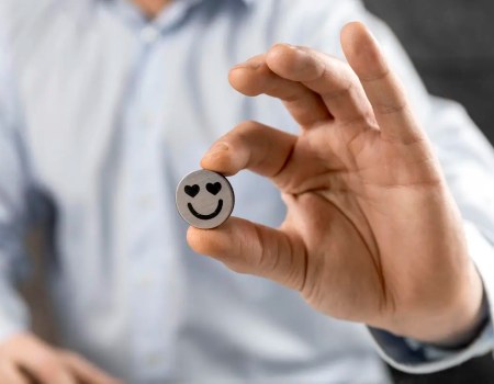 Uma pessoa segurando um botão com corações nos olhos, representando a fidelização de clientes